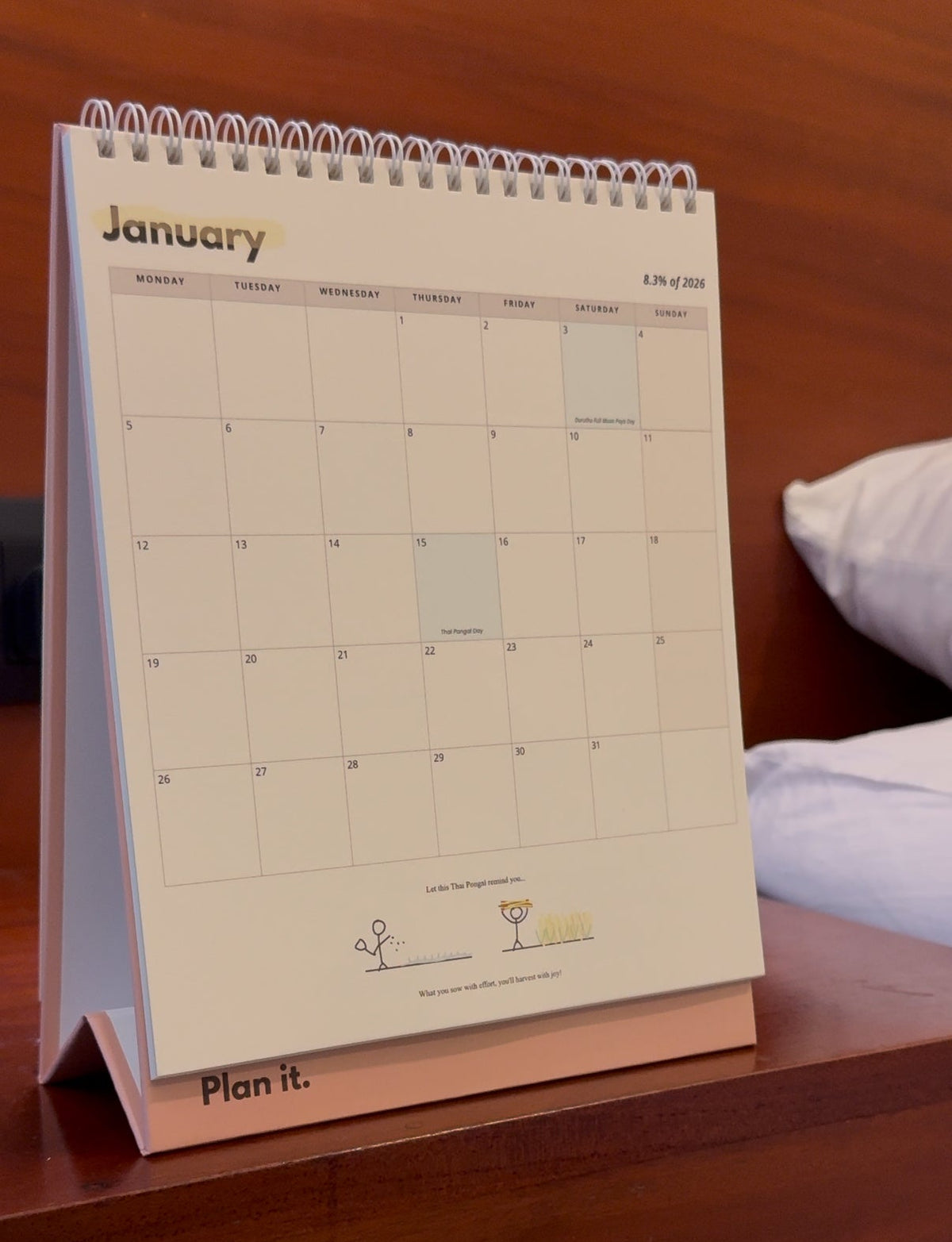 2026 Desktop Calendar on a wooden surface with a bed in the background