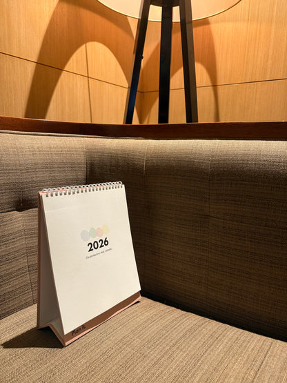 Desktop Calendar for 2026 on a table in a room with wooden walls and a brown cushioned bench in Sri Lanka